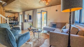 Un vaste espace de vie doté d’un plafond en bois, d’un canapé, d’une table basse et d’un grand lampadaire.