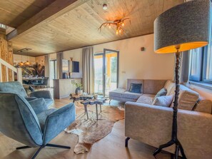 A spacious living area with a wooden ceiling, a sofa, a coffee table, and a large floor lamp.