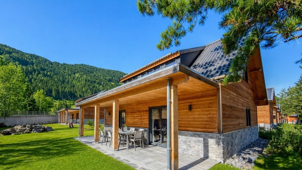 Une maison moderne en bois, dotée d’un patio couvert et de fondations en pierre.