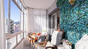 Een balkon met een eettafel, stoelen en een decoratieve muur.