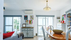 Een moderne keuken met een eetgedeelte, voorzien van een kroonluchter, kasten en kunstwerken aan de wanden.
