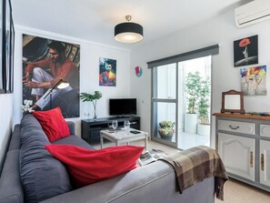 A modern living room with a grey sofa, red cushions, a flat-screen TV, a small coffee table, and a bookshelf. - Sunstay Justin Flat I Torremolinos (Torremolinos)