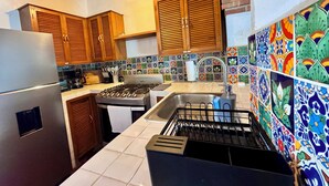 Eine Küche mit Holdelementen, einem Edelstahl-Kühlschrank, einem Gasherd und einer farbenfrohen Fliesenspiegel.
