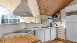A modern kitchen with white cabinets, a wooden countertop, a built-in stove, and a microwave. - "Tonje" - 600m from the sea by Interhome (Løkken)