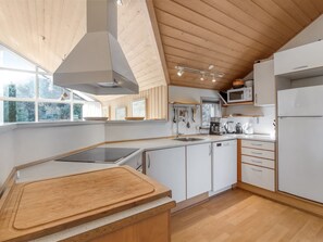 Una cocina moderna con armarios blancos, encimera de madera, estufa integrada y microondas.