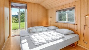 A wooden-paneled room with a bed, a window, and a door leading to a balcony. - "Tonje" - 600m from the sea by Interhome (Løkken)