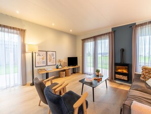 A modern living room with a fireplace, a TV, and a sofa. - Holiday home by the water in the Green Heart (Oud Ade)