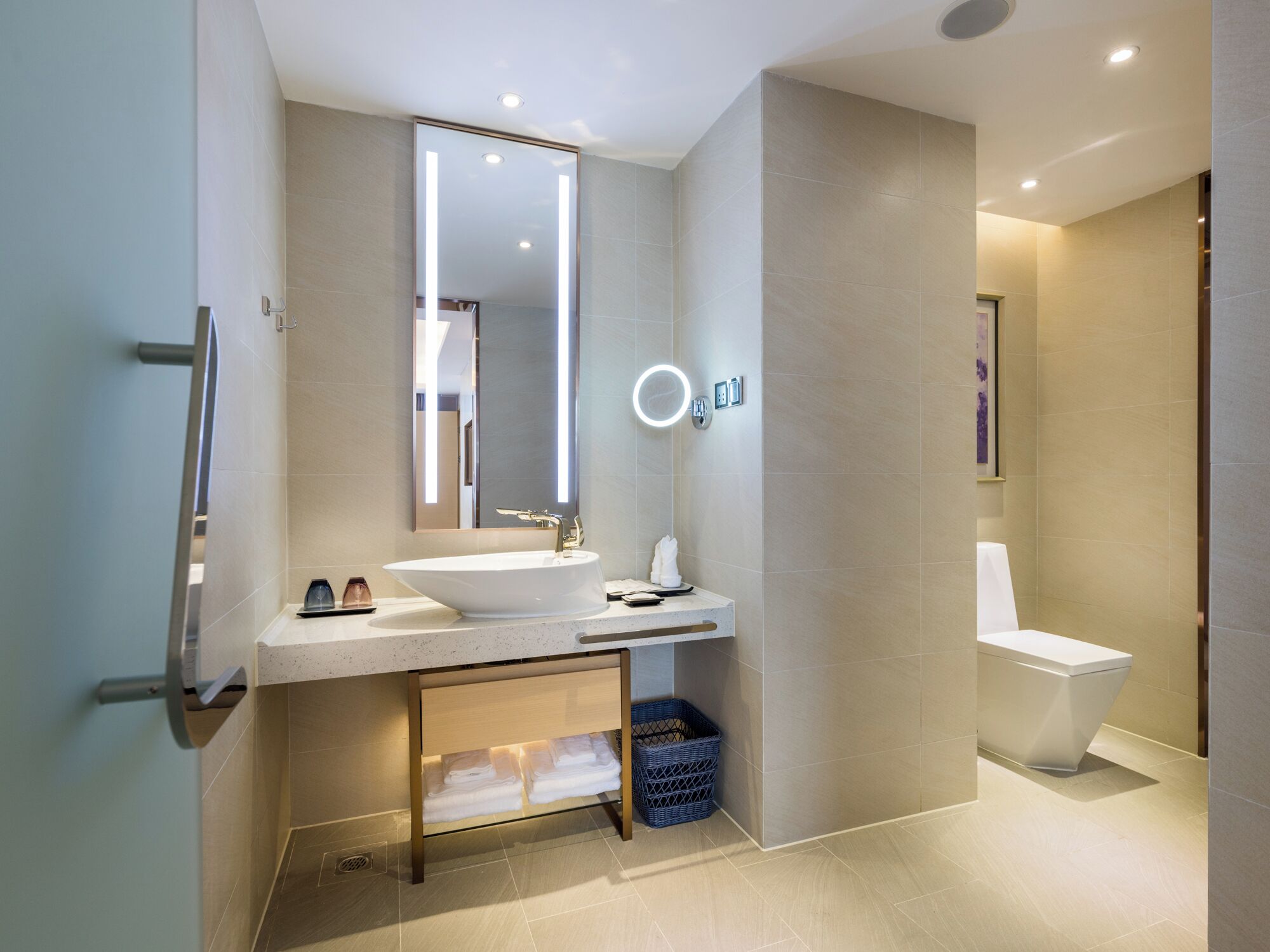 Une salle de bain moderne avec un grand miroir, un lavabo, des toilettes et un meuble en verre placé sous le lavabo.