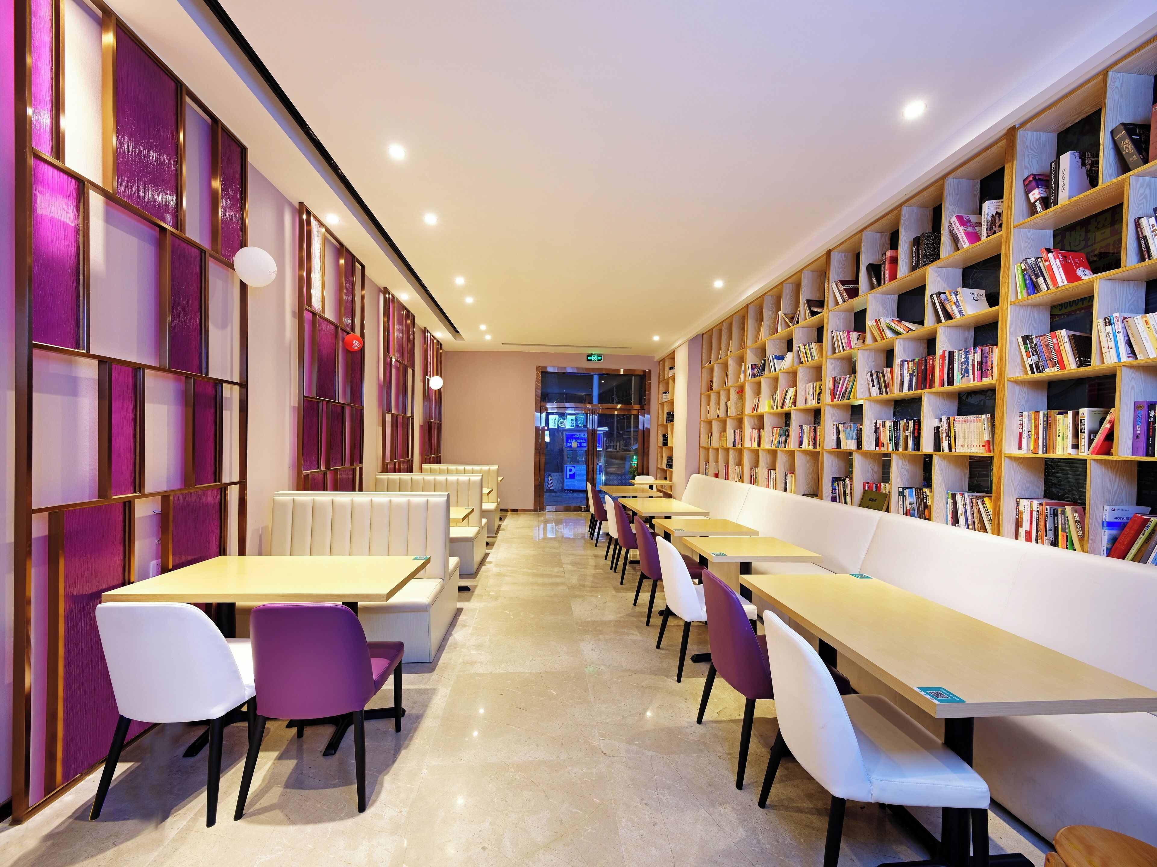 A modern library with rows of tables and chairs, and bookshelves filled with books.