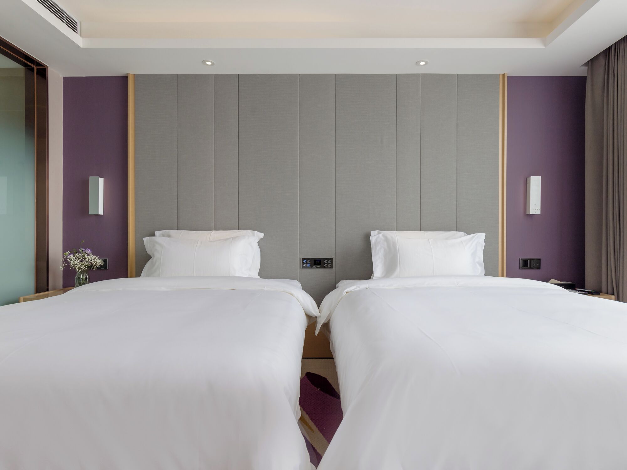 A hotel room with two beds, a modern design, and a neutral color palette.