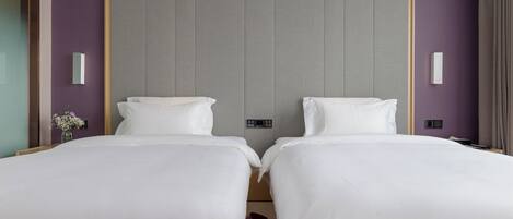 Habitación de hotel con dos camas, diseño moderno y colores neutros.