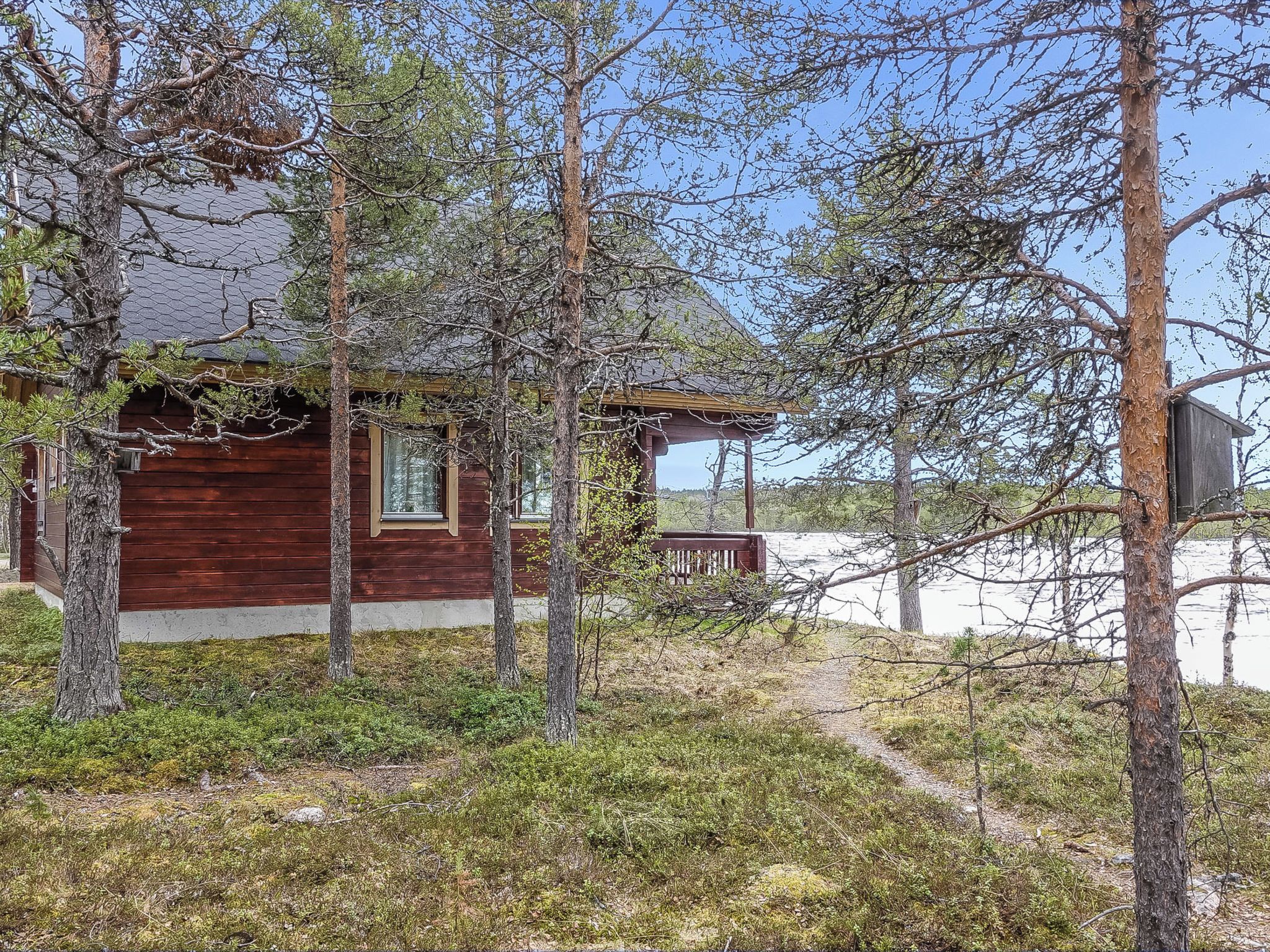 Een houten chalet met een veranda, omgeven door bomen en een heldere lucht.