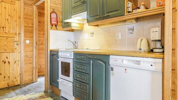 Une cuisine avec des meubles de rangement en bois, une cuisinière, un lave-vaisselle et une machine à café.