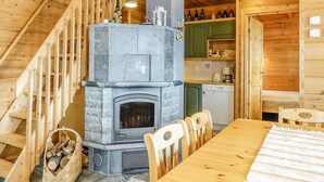 A wooden interior with a stone fireplace, wooden staircase, and a dining area.