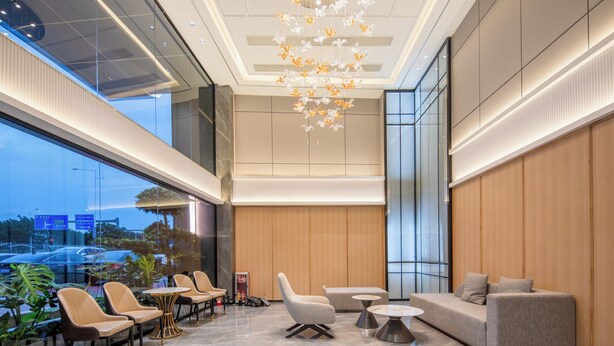 A modern hotel lobby with seating areas, a chandelier, and large windows offering a view of the street. - Mant International Hotel Ancient Whampoa Anchorage Scenic Spot Canton Fair Complex Branch (Guangzhou)