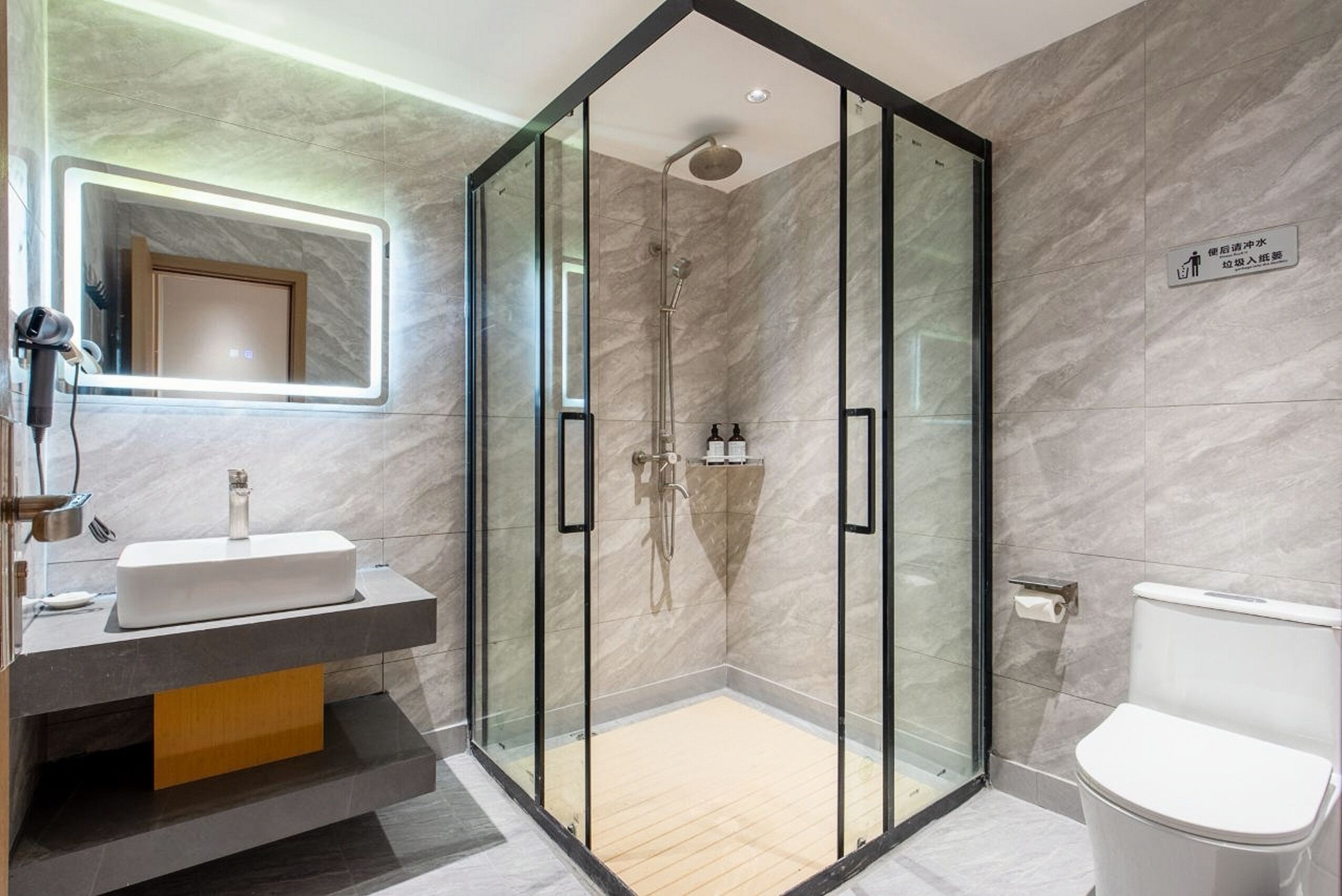 A modern bathroom with a glass-enclosed shower, a white sink, and a toilet.