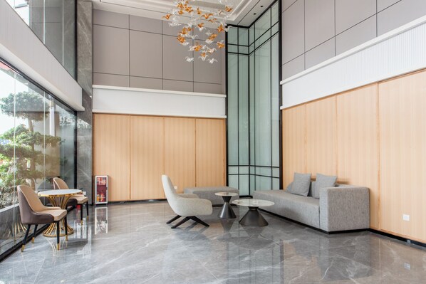 A modern lobby with a seating area, a glass wall, and a wooden panel wall. - Mant International Hotel Ancient Whampoa Anchorage Scenic Spot Canton Fair Complex Branch (Guangzhou)