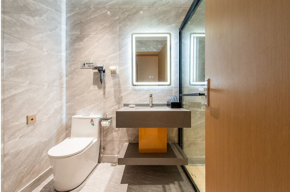 A modern bathroom with a toilet, sink, and mirror.