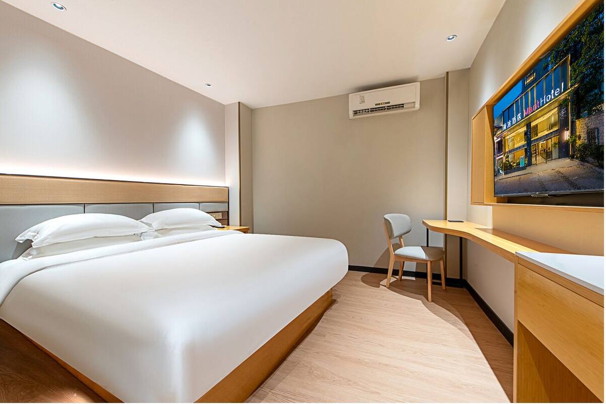Une chambre d’hôtel avec un grand lit, un bureau, une chaise et un téléviseur.