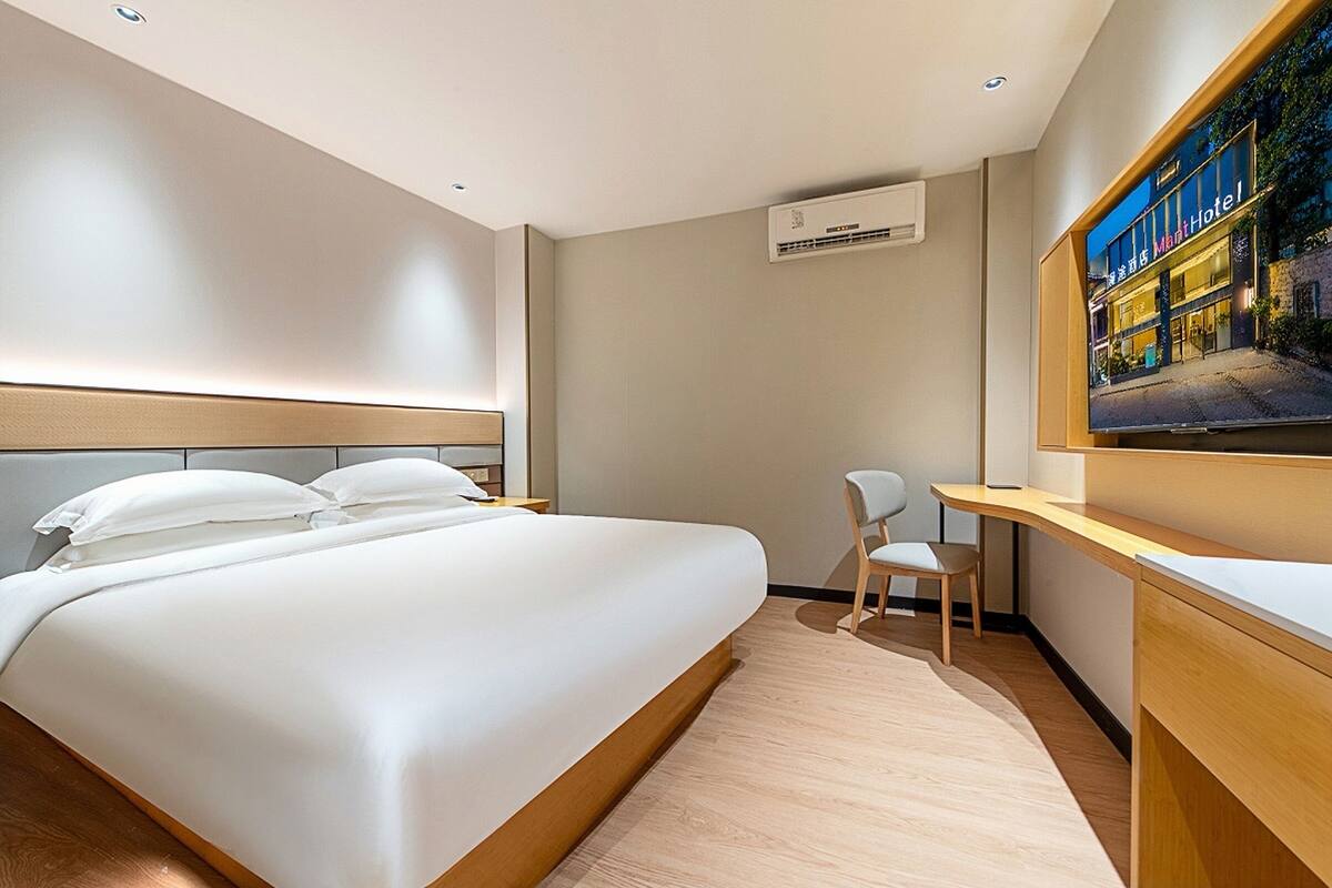 Une chambre d’hôtel avec un grand lit, un bureau, une chaise et un téléviseur.