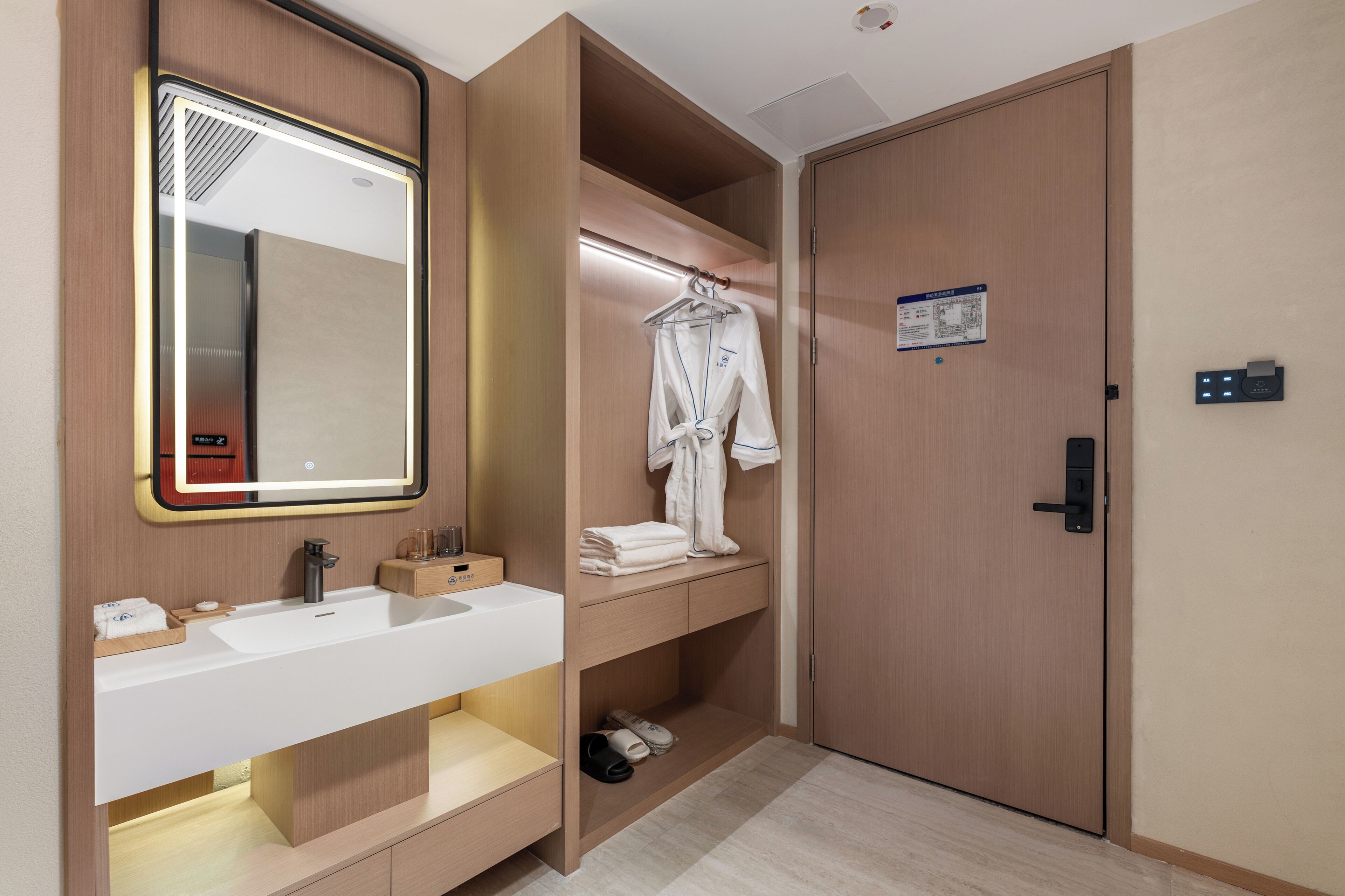 A modern bathroom with a large mirror, a sink, and a robe rack.