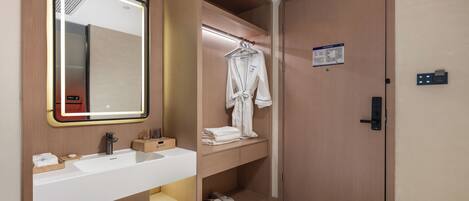 A modern bathroom with a large mirror, a sink, and a robe rack.