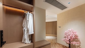 A hotel room with a wooden wardrobe, a hanging robe, a small table, and a decorative tree. - PIN Hotel Guangzhou Beijing Road Pedestrian Street Peasant Movement Institute Metro Station Branch (Guangzhou)