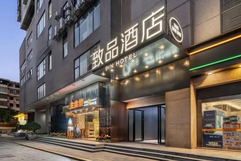 Un hotel con fachada moderna, entrada visible y un letrero que indica que es un Pin Hotel.