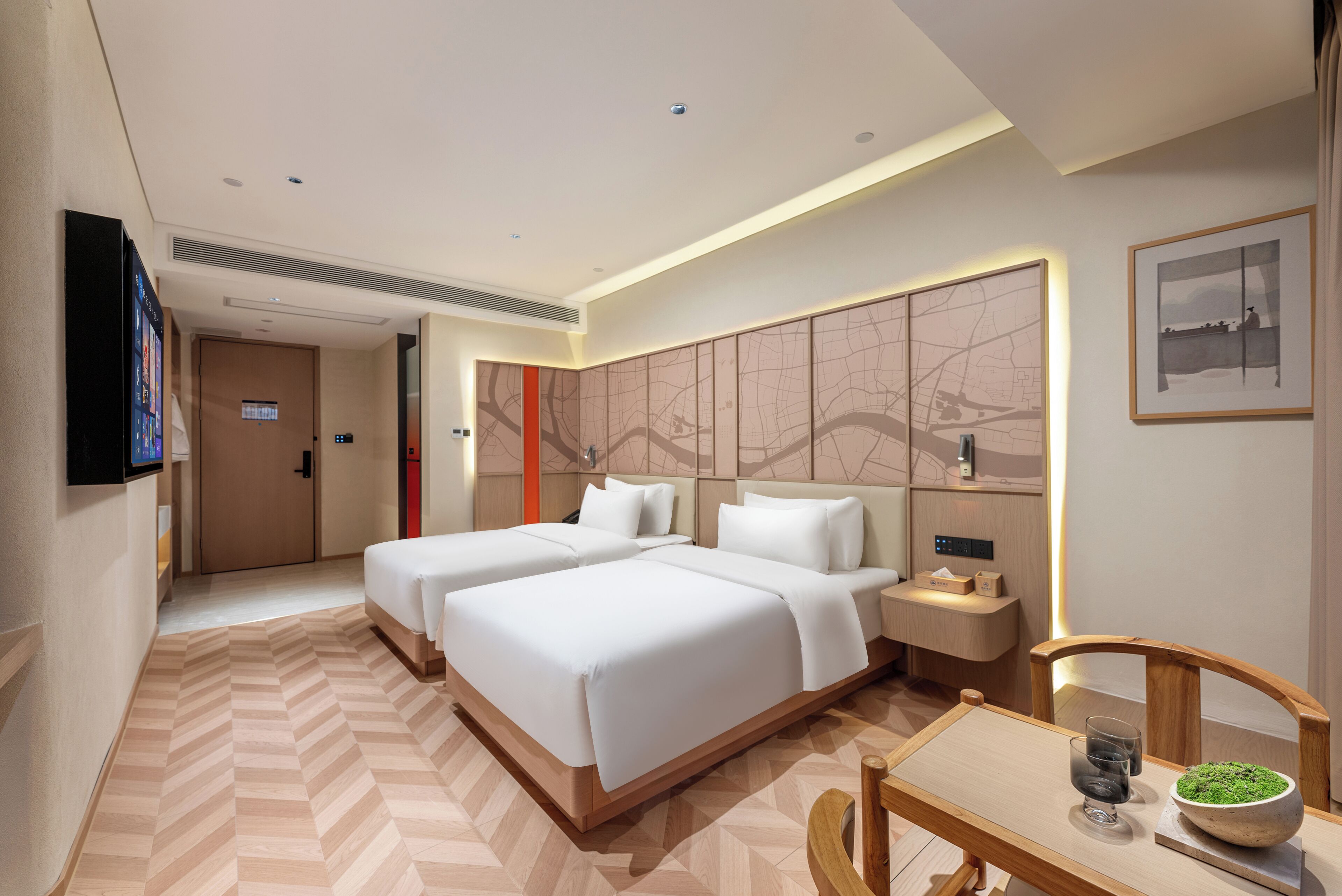 A hotel room with two beds, a desk, a chair, a TV, and a wall with a map design.