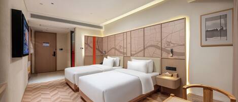 A hotel room with two beds, a desk, a chair, a TV, and a wall with a map design.