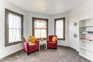 A room with two red chairs, a small white table, and a bookshelf. - Walkable Location, Historic Setting: Warrenton Apt (Warrenton)