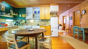 Una cocina acogedora con armarios de madera, una mesa de comedor, sillas y un refrigerador.