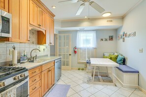 Una cocina con armarios de madera, un microondas, una estufa y una zona de comedor con un banco.