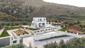 Eine moderne Villa mit Pool, umgeben von Olivenbäumen und Hügeln.