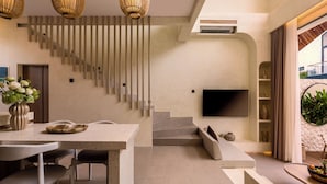 A modern interior with a staircase, seating area, and a flat-screen TV mounted on the wall. - Villa Fresko 2 by Alfred in Bali (Munggu)