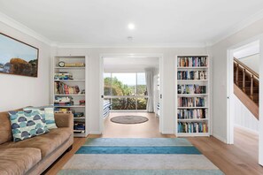 Ein Wohnzimmer mit einer Couch, einem Bücherregal und Blick ins Freie.
