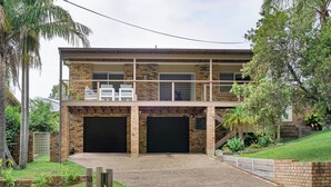Ein zweistöckiges Haus mit Garage, Balkon und gepflegtem Rasen.