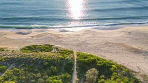 Uma praia com um caminho que leva a uma área de dunas.