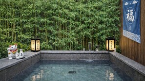 A traditional Japanese onsen with a bamboo backdrop, a stone bath, and a Maneki-neko statue. - Stay Passport Tokyo Ryokan Seoul Sadang (Seoul)