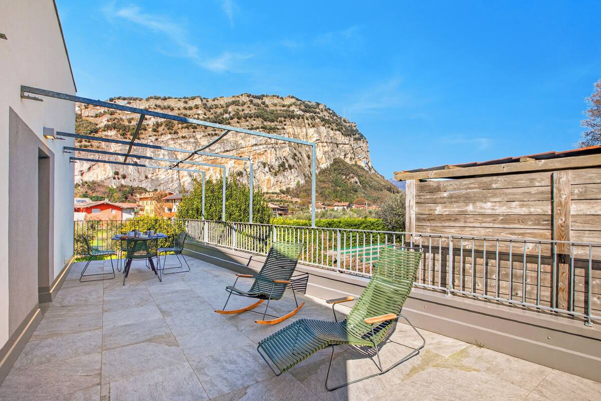 A balcony with two rocking chairs, a table, and a view of a mountainous landscape.