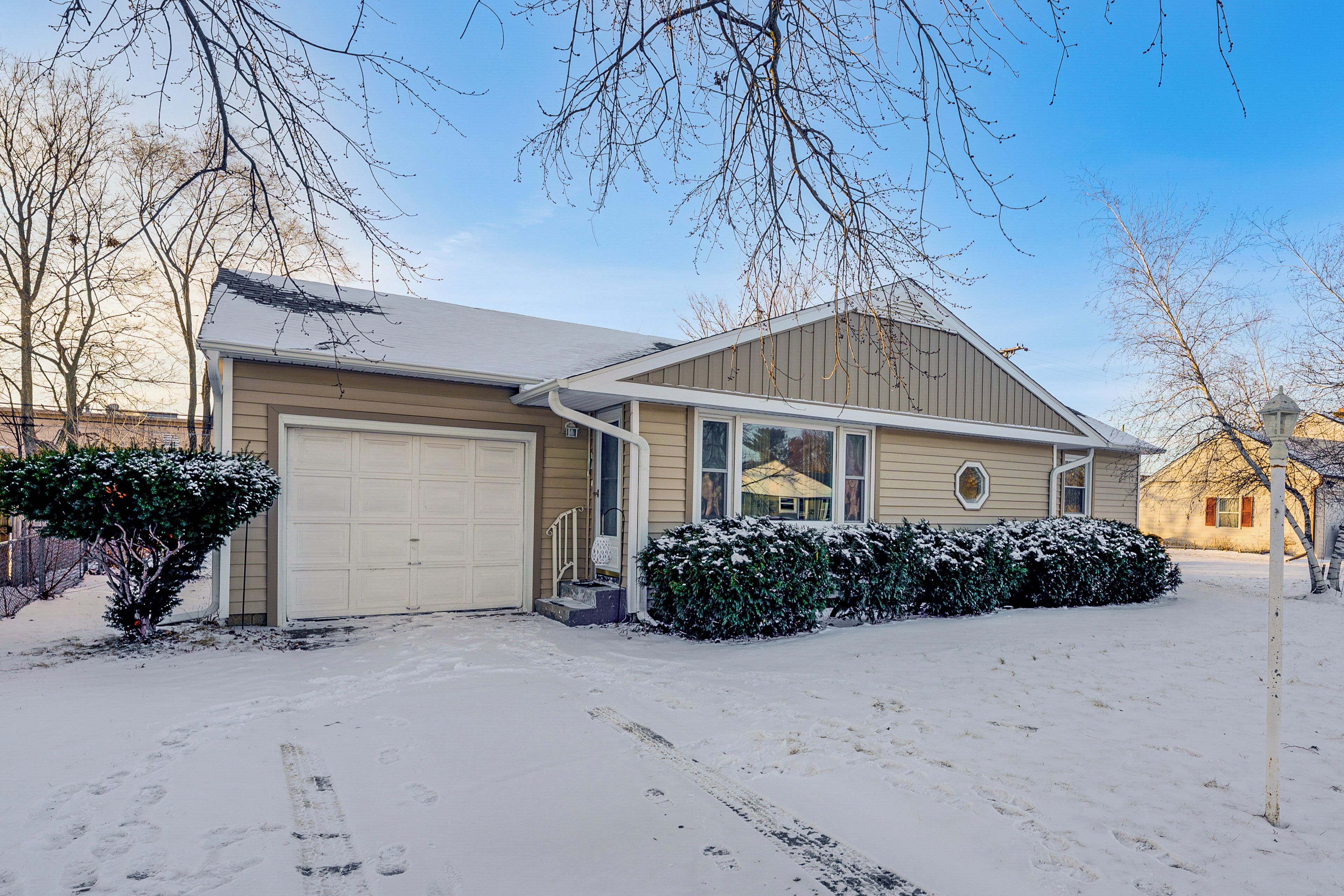A two-story house with a garage, a covered porch, and a snow-covered driveway.