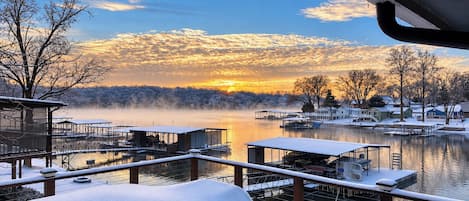 Une scène hivernale avec un quai et des bâtiments au bord d’un lac, le tout recouvert de neige.