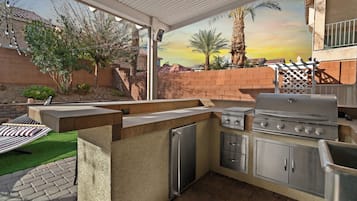 Outdoor kitchen and grill station with built-in BBQ, countertops and sink, perfect for alfresco cooking and dining. Prepare delicious meals while enjoying the resort-style backyard and desert sunsets.