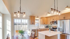 Una cocina moderna con armarios de madera, electrodomésticos de acero inoxidable e iluminación colgante.