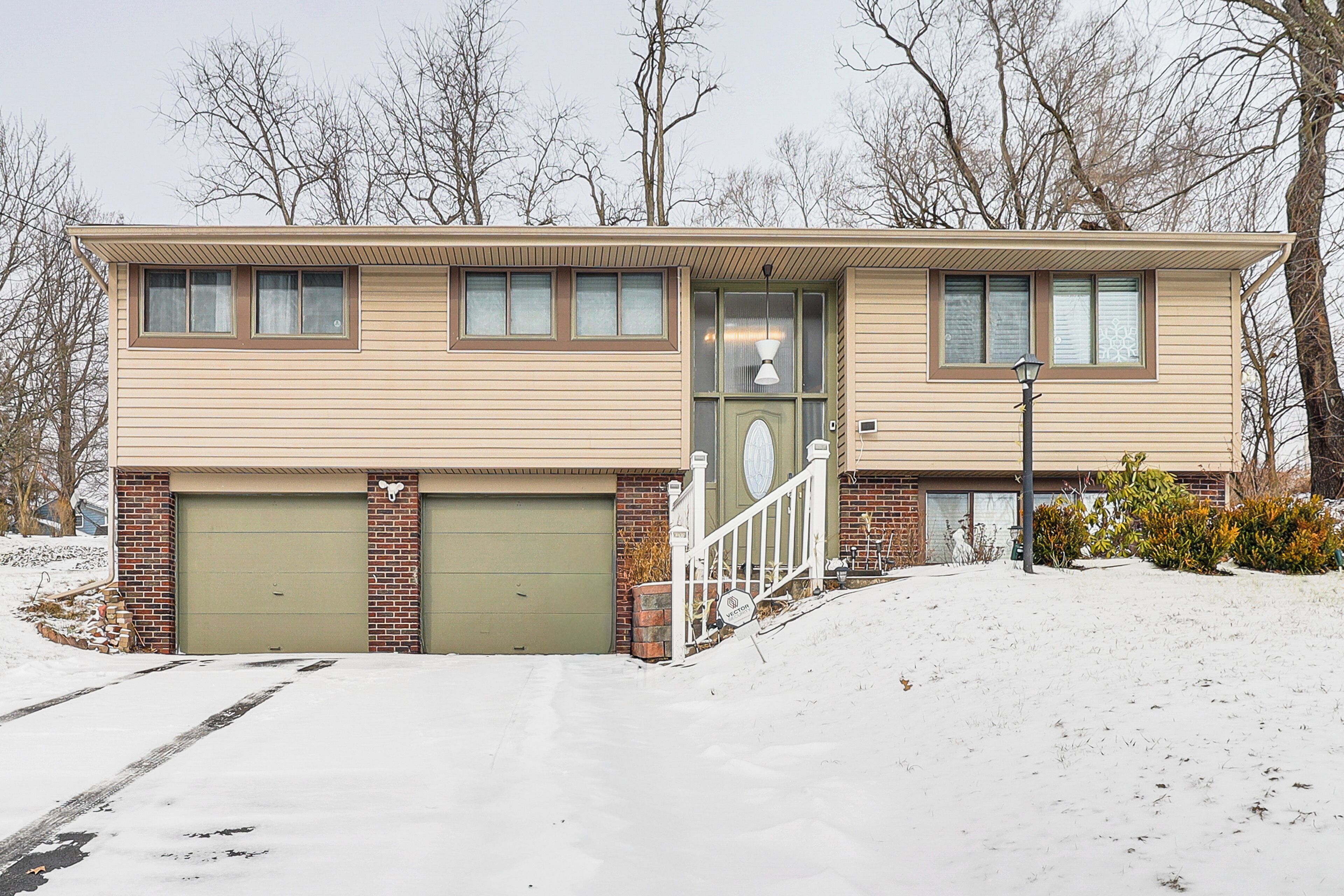 A two-story house with a garage, a front porch, and a snow-covered driveway.