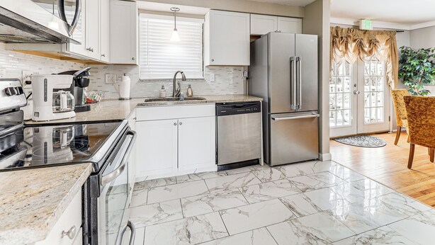 A modern kitchen with white cabinets, stainless steel appliances, and a marble floor. - Remote-Work Ready: Family Home Near Pittsburgh (Monroeville)