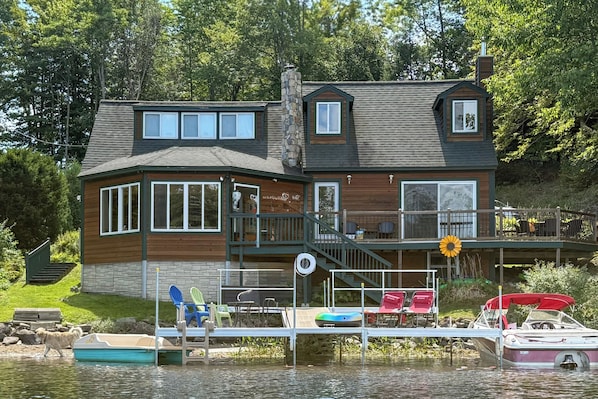 A two-story house with a dock, a boat, and a dog walking by. - Dock & Views! Lakeside Family Escape in Wilton (Wilton)