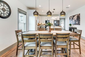 A dining area with a wooden table and chairs, pendant lights, and a large wall clock. - Walk to Beach! 'Ocean's Paradise' w/ Patio (Mexico Beach)