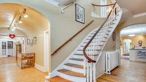 Eine imposante Treppe mit weißen Geländern und Holzstufen, die zu einer oberen Etage führt.