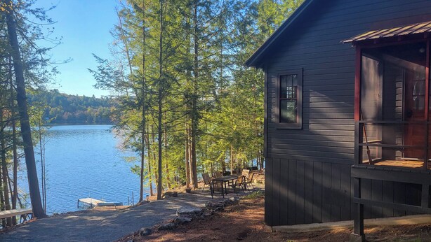 Una cabaña con muelle, mobiliario exterior y vista al lago.